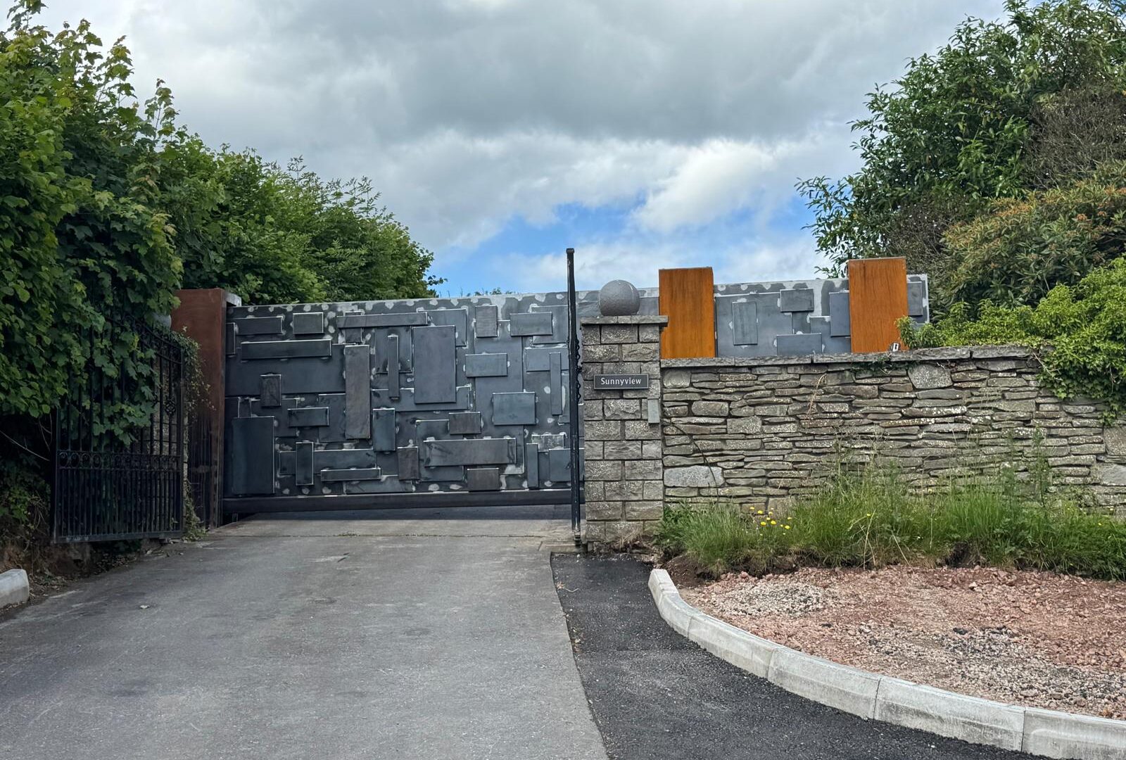 Corten steel panel driveway gates with stone pillars