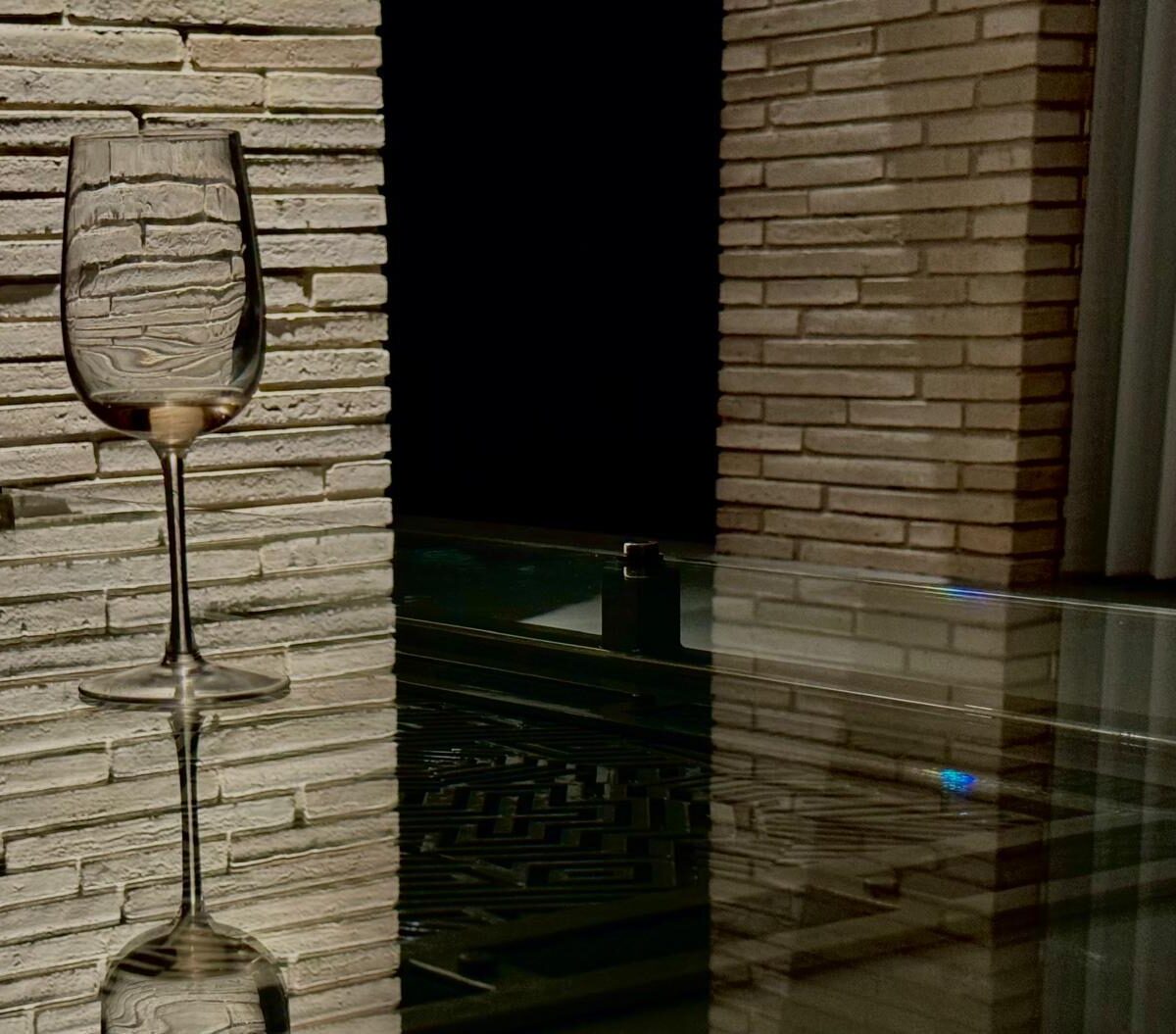 Glass topped steel table against a stone wall