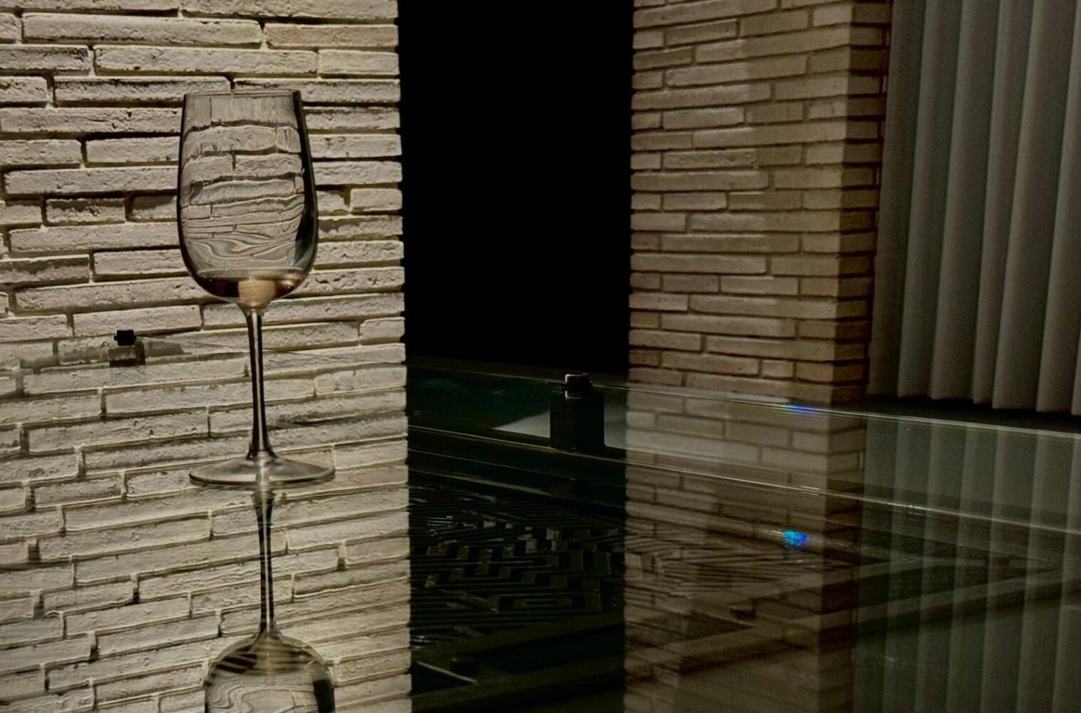 Glass topped steel table against a stone wall
