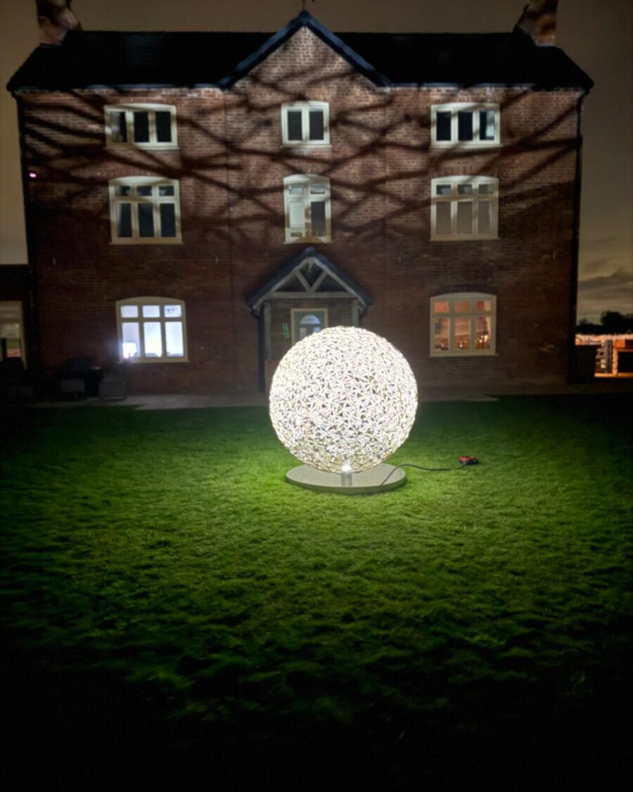 Illuminated garden sphere in front of a farmhouse at night
