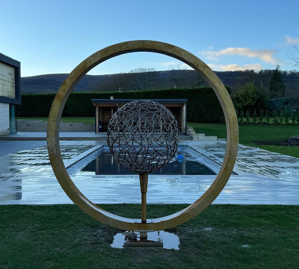 Moon gate and lattice sphere by the pool, wide view
